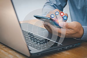 Social media and digital online concept. Closeup of businessman hand touching mobile smartphone and laptop computer with icon