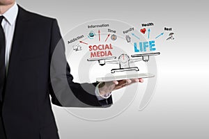 Social media life balance. Chart with keywords and icons. Man holding a tablet computer