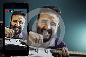 Social media live streaming concept, Guitarist recording a video of himself while playing an electric guitar in studio