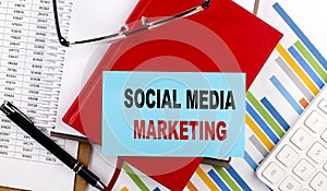 SOCIAL MEDIA MARKETING text on a sticky on red notebook on chart background