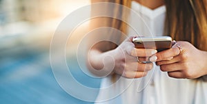 Social networking. an unrecognizable young woman sending a text message while standing outside.