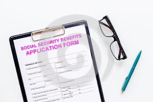 Social security benefits. Application form near pen and glasses on white background top view