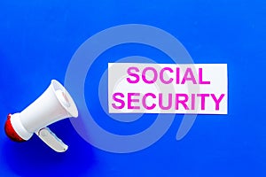 Social security concept. Printed words social security near megaphone on blue background top view copy space
