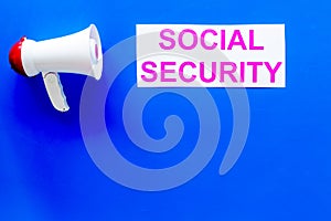 Social security concept. Printed words social security near megaphone on blue background top view copy space