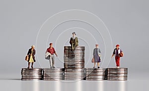 Miniature people with stack of coins. photo