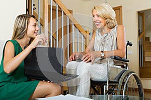 Social worker and handicapped woman with laptop