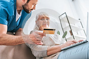 social worker holding credit card and looking at senior woman