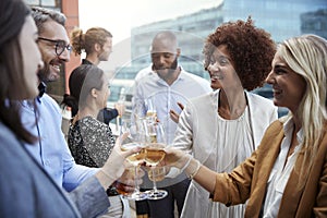 Socialising office colleagues raising glasses and making a toast with drinks after work