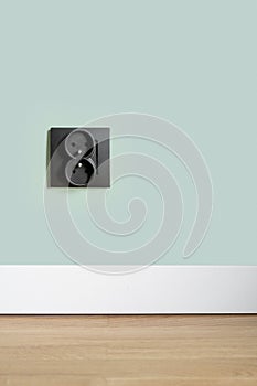 Socket in black plastic frame on green wall