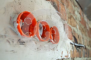 Socket orange boxes with wires in a wall. Cabling installation of electrical wires sticking out from electrical sockets hole on