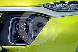 Socket plug connecting on front of yellow smart vehicle EV for connect to electric charger machine for rechargeable battery