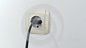 Socket plug with electric plug line on white wall