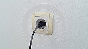 Socket plug with electric plug line on white wall