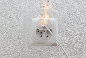 Socket or wire plug malfunction burning phone charger in indoor, electric short circuit causing fire on plug socket