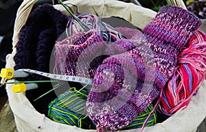 Socks knitting concept: Close up of wool balls, knitted socks, measuring tape and knit needles in basket