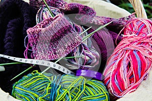 Socks knitting concept: Close up of wool balls, knitted socks, measuring tape and knit needles in basket