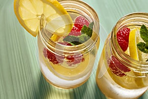 Soda with lemon, berries and mint on green table