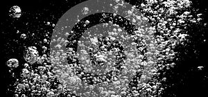 Soda water bubbles splashing underwater against black background