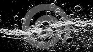 Soda water bubbles splashing underwater against black background