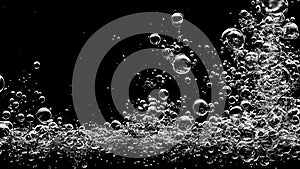 Soda water bubbles splashing underwater against black background