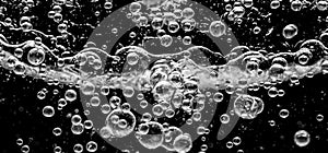 Soda water bubbles splashing underwater against black background photo