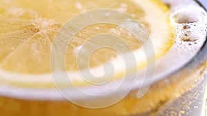 Soda water pouring into slice lemon in a drinking glass in slow motion