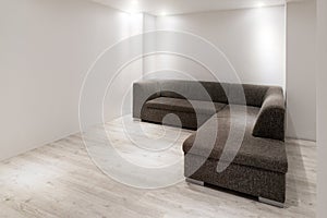 Sofa with chaiselongue in empty renovated apartment