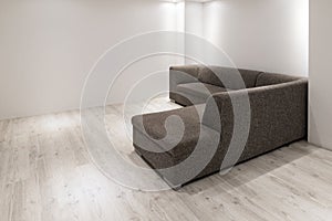 Sofa with chaiselongue in empty renovated apartment