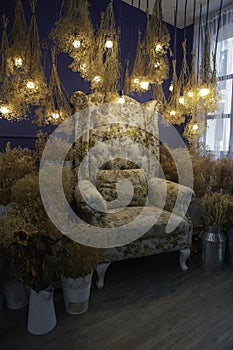 Sofa, dry yellow flowers and light bulb hanging.