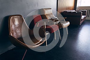 A sofa made of artificial leather on the background of a window and a wall with wooden panels. A sofa and three