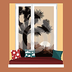 The sofa on the window sill with the mountains desert view. Morning landscape with Joshua tree and mountains over