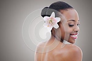 Soft as a petal. Studio portrait of a beautiful african american model with an orchid against a gray background.