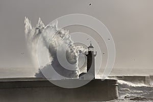 Soft backlit sea wave splash over old lighthouse