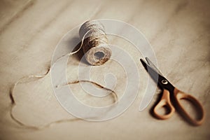 On the soft beige fabric there are scissors and a skein of strong hemp rope. The process of sewing and creating