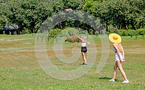 Soft blur of two teen girls play with kite in grass field of park or garden with day light