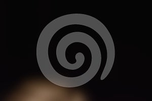 Soft blurred warm light floating in deep darkness.