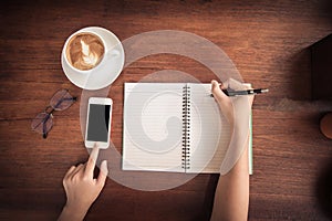 Soft and blurry, top view, teenager hand, writing pencil holder, cell phone touching, Black space for text, Rounded vintage glasse