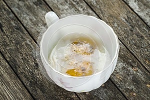 Soft boiled egg in cup on wooden background.