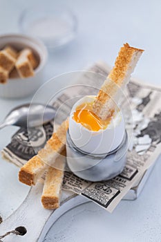 Soft-boiled egg in an eggcup with toasts on the wooden background, selective focus