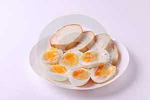 Soft boiled egg halves on the white plate and bread slices