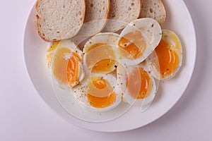 Soft boiled egg halves on the white plate and bread slices