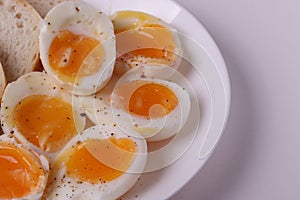 Soft boiled egg halves on the white plate and bread slices