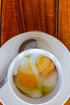 Soft boiled egg in white cup with spoon