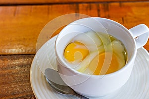 Soft boiled egg in white cup with spoon
