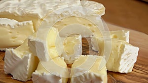 Soft brie cheese cubes on rustic wooden board