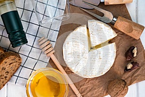 Soft cheese Camembert, honey, nuts and bottle of wine on the table for dinner. Close-up. Top view. Selective focus