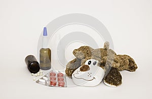 Soft children`s toy dog with medicines and tablets next to it. Concept of children`s health and diseases, protection of children f