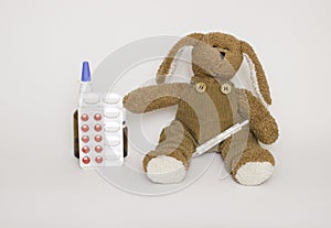 Soft children`s toy dog with medicines and tablets next to it. Concept of children`s health and diseases, protection of children f