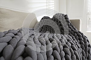 Soft chunky knit blanket on sofa in room, closeup