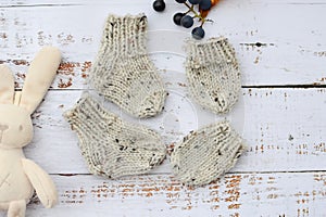 Soft and chunky, warm baby socks, hand-knitted, on white wooden background